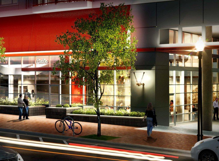 Rendering of building exterior at nighttime. Street view of leasing office and sidewalk.
